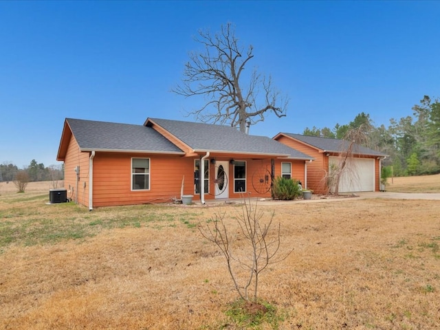 ranch-style home with a porch, a garage, a front lawn, and central air condition unit