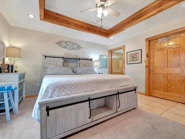 bedroom featuring ceiling fan, light colored carpet, connected bathroom, and a tray ceiling