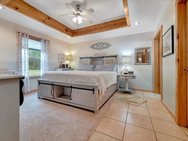 tiled bedroom featuring ceiling fan and a tray ceiling