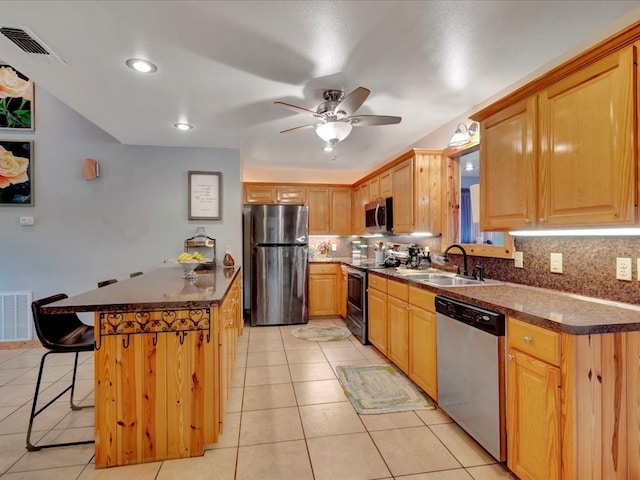 kitchen with sink, a breakfast bar, stainless steel appliances, light tile patterned flooring, and decorative backsplash