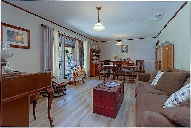 living room featuring a textured ceiling, light wood-type flooring, and ornamental molding