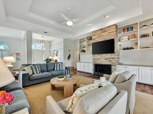 301 Sawgrass Cir, Lufkin, TX 75901 - living room featuring a tray ceiling, ceiling fan, ornamental molding, a stone fireplace, and wood finished floors