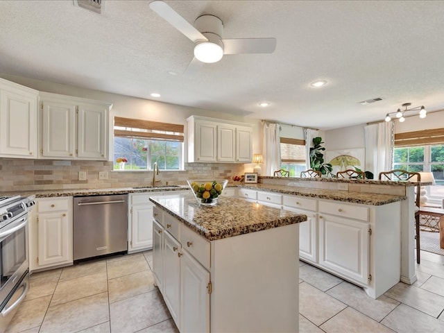 301 Sawgrass Cir, Lufkin, TX 75901 - kitchen featuring appliances with stainless steel finishes, a peninsula, plenty of natural light, a kitchen island, and a textured ceiling