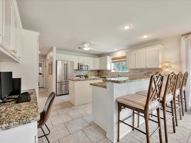 301 Sawgrass Cir, Lufkin, TX 75901 - kitchen with appliances with stainless steel finishes, decorative backsplash, a peninsula, light stone countertops, and recessed lighting