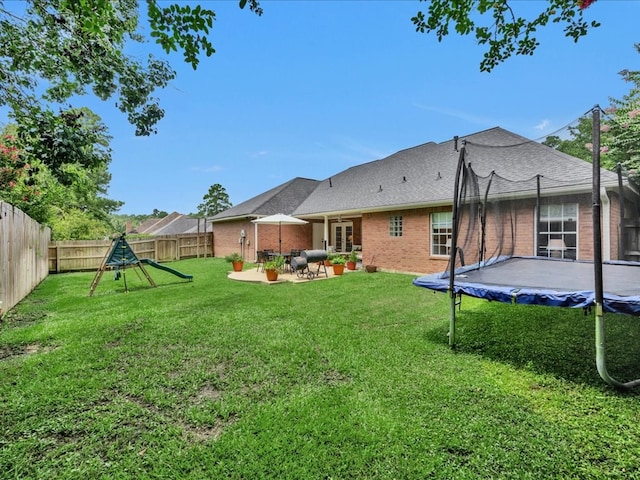 301 Sawgrass Cir, Lufkin, TX 75901 - back of house with a trampoline, brick siding, a patio area, and a fenced backyard