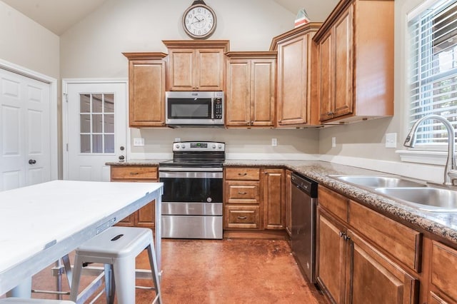 kitchen featuring a breakfast bar, sink, appliances with stainless steel finishes, and vaulted ceiling