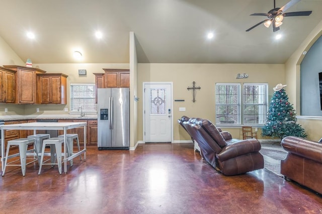 kitchen with ceiling fan, sink, a kitchen breakfast bar, high vaulted ceiling, and stainless steel refrigerator with ice dispenser