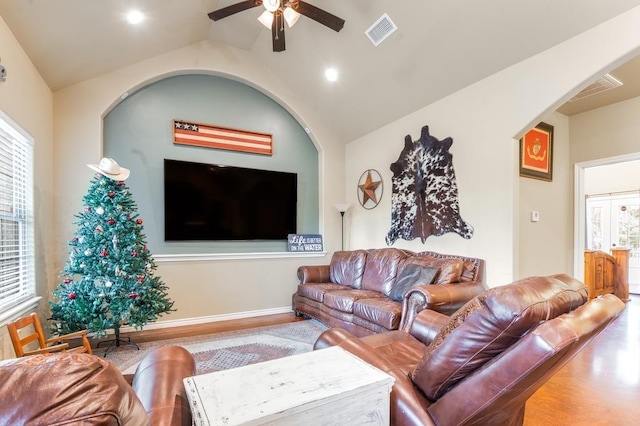 living room with a wealth of natural light, hardwood / wood-style floors, ceiling fan, and lofted ceiling