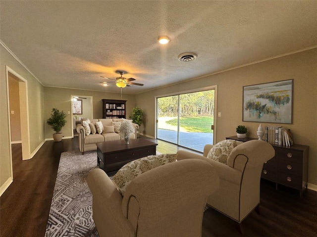 living room with crown molding, ceiling fan, dark wood-type flooring, and a textured ceiling