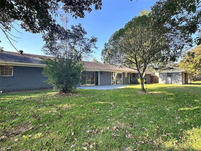 back of house with a storage unit, a patio, and a lawn