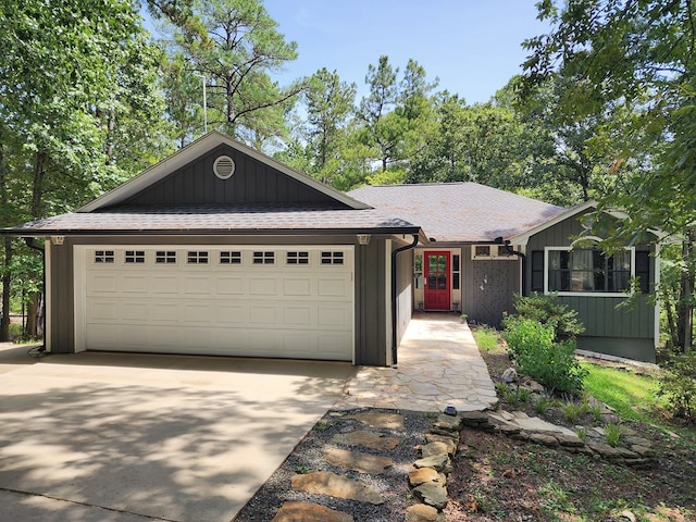 203 Bogey Ln, Brookeland, TX 75931 - view of front of home with an attached garage, concrete driveway, a shingled roof, and board and batten siding