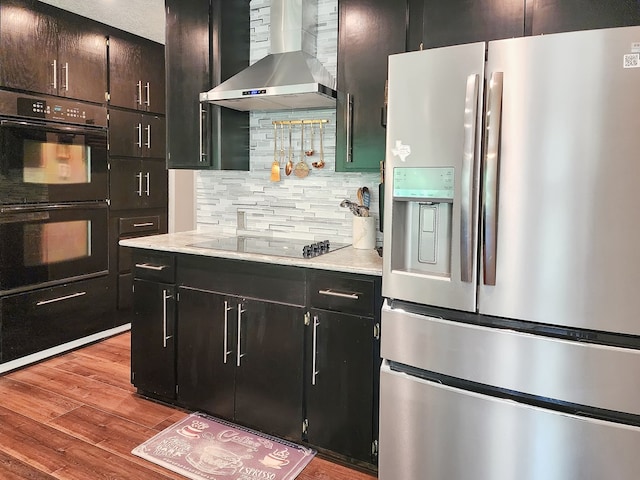 203 Bogey Ln, Brookeland, TX 75931 - kitchen with black appliances, wall chimney range hood, backsplash, wood finished floors, and light countertops