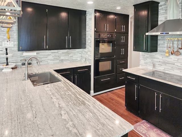 203 Bogey Ln, Brookeland, TX 75931 - kitchen with wall chimney range hood, black appliances, dark cabinetry, backsplash, and wood finished floors