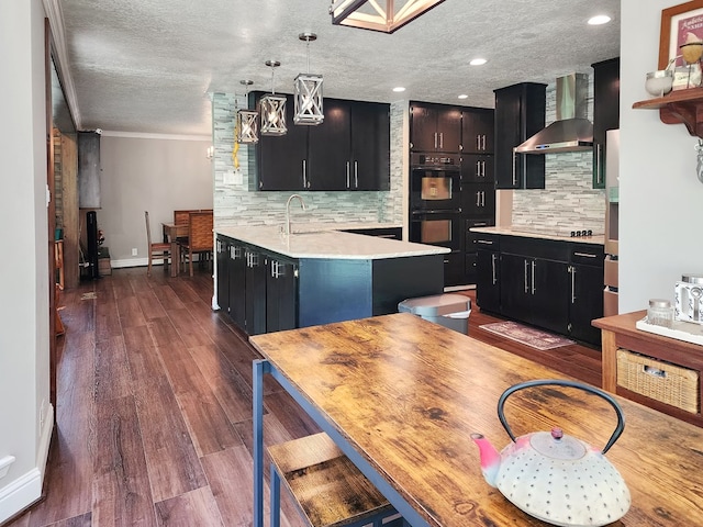203 Bogey Ln, Brookeland, TX 75931 - kitchen with black appliances, wall chimney range hood, dark cabinetry, light countertops, and tasteful backsplash