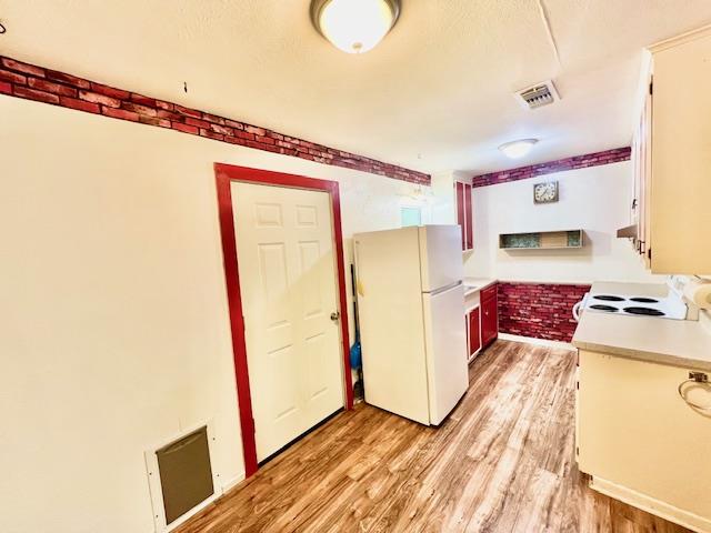 kitchen with white appliances and light hardwood / wood-style flooring