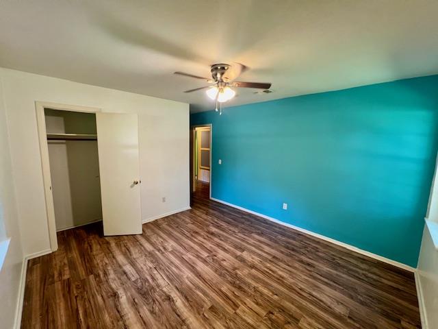 unfurnished bedroom featuring dark hardwood / wood-style flooring, a closet, and ceiling fan