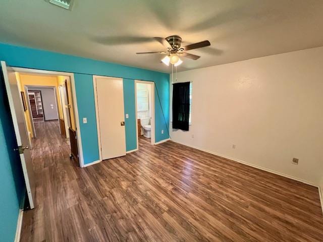 unfurnished bedroom featuring ensuite bathroom, ceiling fan, and dark wood-type flooring