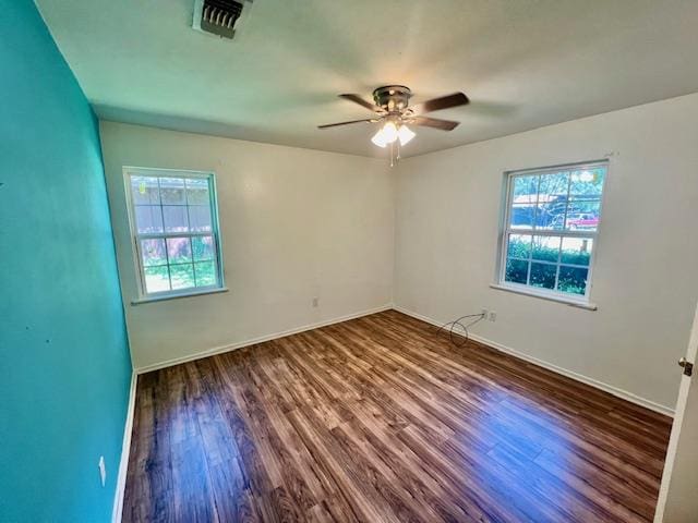 unfurnished room with ceiling fan, a healthy amount of sunlight, and dark wood-type flooring