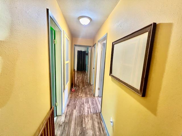 hallway featuring hardwood / wood-style flooring and a textured ceiling