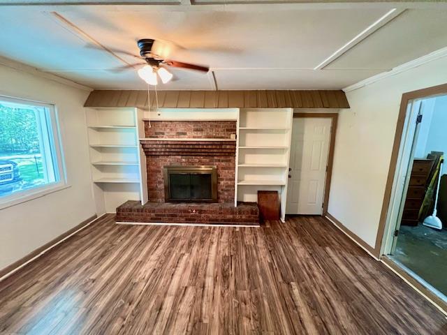 unfurnished living room featuring a fireplace, ceiling fan, crown molding, and dark wood-type flooring