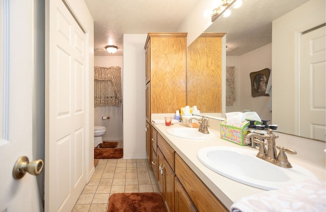 bathroom featuring tile patterned floors, vanity, a textured ceiling, and toilet