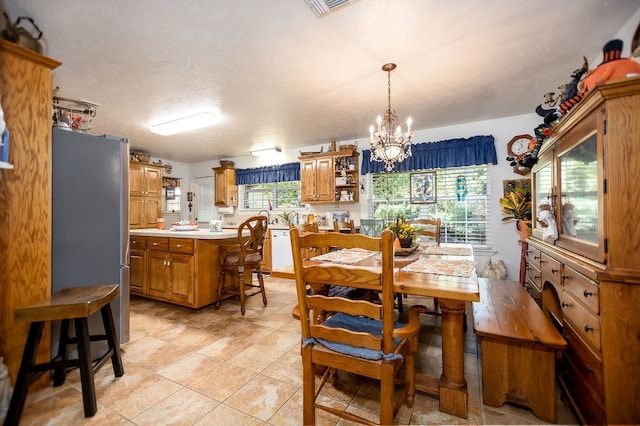 tiled dining room with a notable chandelier and a textured ceiling