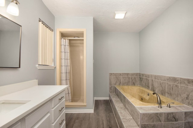 bathroom featuring wood-type flooring, vanity, shower with separate bathtub, and a textured ceiling