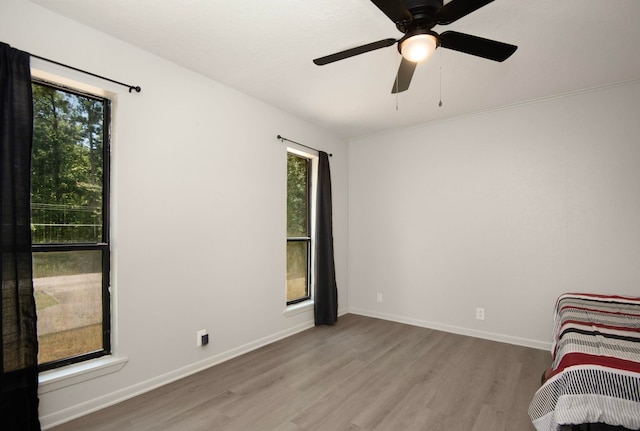unfurnished bedroom with multiple windows, light wood-type flooring, and ceiling fan
