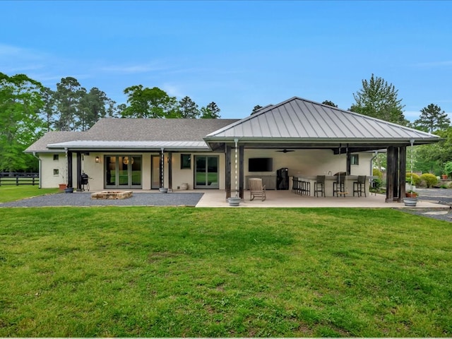 rear view of house with exterior bar, a lawn, a patio area, and ceiling fan