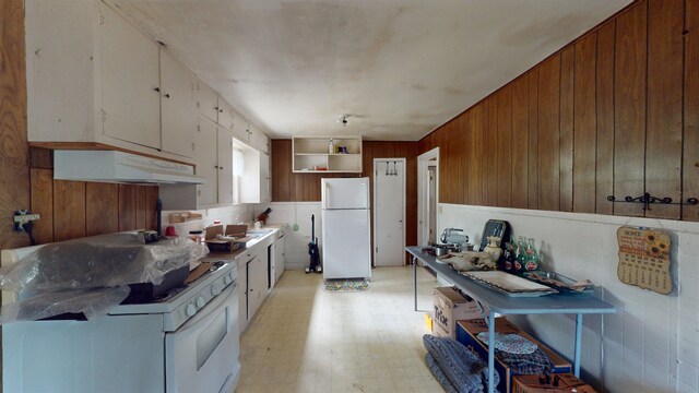 kitchen with white cabinets, white appliances, wooden walls, and sink