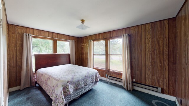 bedroom featuring wooden walls, dark carpet, and a baseboard radiator