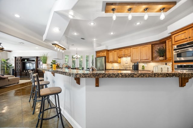 205 Twin Crk, Lufkin, TX 75904 - kitchen featuring freestanding refrigerator, a breakfast bar, brown cabinetry, recessed lighting, and crown molding