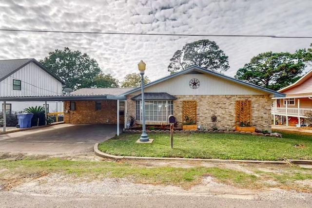 ranch-style home featuring a carport, brick siding, and a front yard