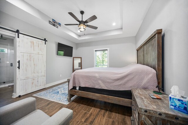 1065 Cc Rd, Diboll, TX 75941 - bedroom with a barn door, baseboards, wood finished floors, a tray ceiling, and ceiling fan