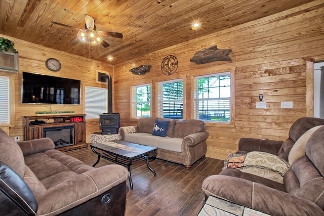 living room featuring dark hardwood / wood-style flooring, ceiling fan, wooden ceiling, a wood stove, and wood walls