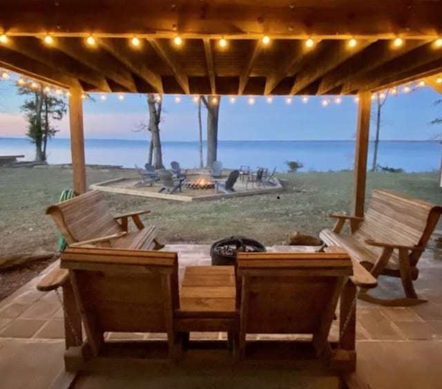 patio terrace at dusk featuring a water view and a fire pit