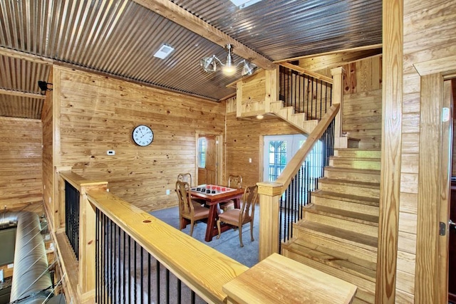 staircase featuring a skylight, beamed ceiling, carpet floors, wooden walls, and wood ceiling