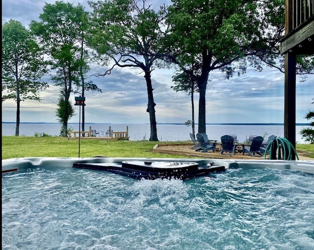 view of swimming pool featuring a water view, a hot tub, and a lawn