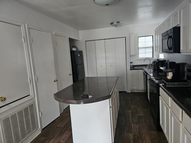 2540 Brentwood Dr, Lufkin, TX 75901 - kitchen with black appliances, dark wood-style flooring, white cabinets, and a center island