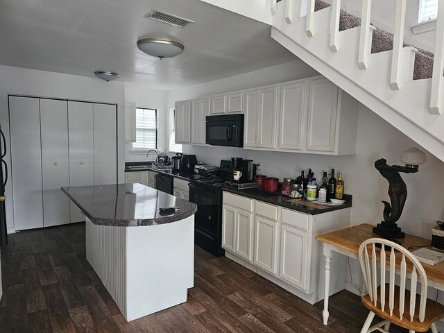 2540 Brentwood Dr, Lufkin, TX 75901 - kitchen with black appliances, dark countertops, dark wood-style floors, white cabinets, and a center island