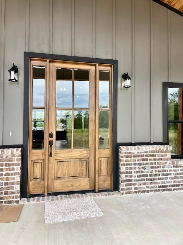 doorway to property featuring board and batten siding and brick siding