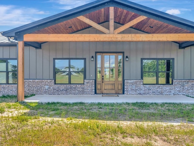 property entrance featuring board and batten siding and brick siding