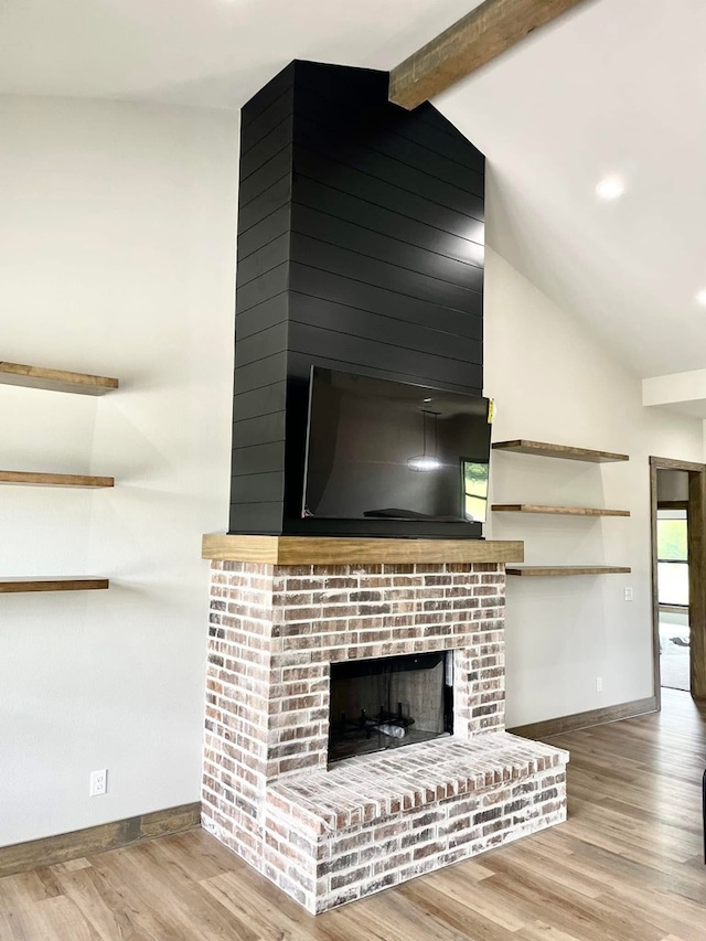 details featuring wood finished floors, baseboards, beam ceiling, and a brick fireplace