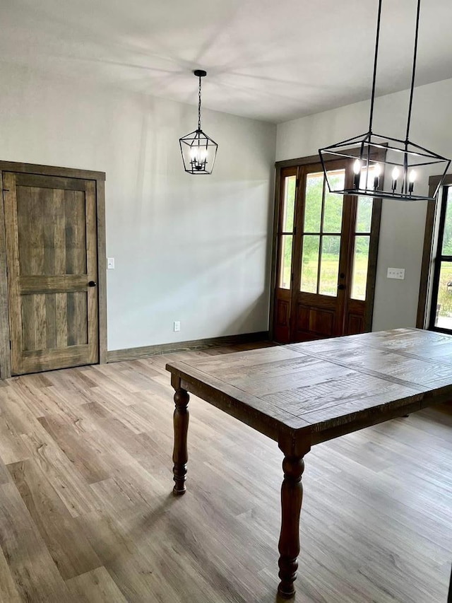 dining space with wood finished floors, baseboards, and a notable chandelier