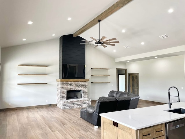 kitchen with stainless steel dishwasher, a sink, a fireplace, open floor plan, and ceiling fan