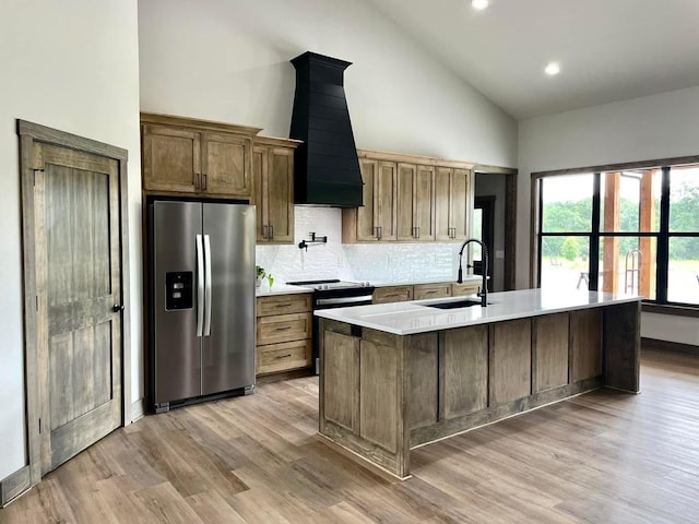 kitchen with high vaulted ceiling, a sink, backsplash, wall chimney exhaust hood, and appliances with stainless steel finishes