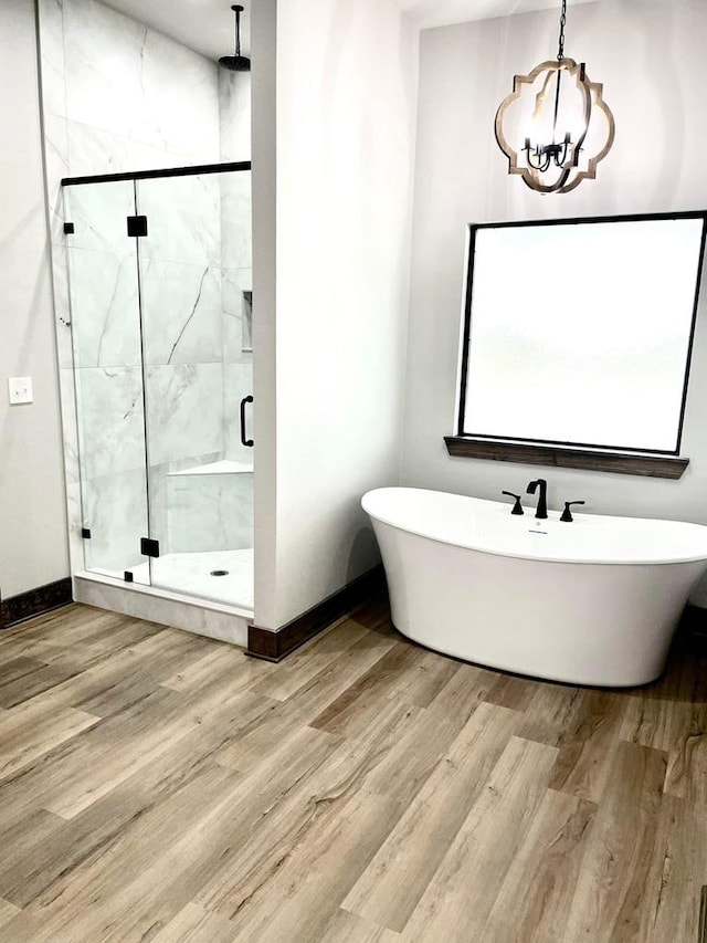 bathroom featuring a soaking tub, wood finished floors, and a marble finish shower