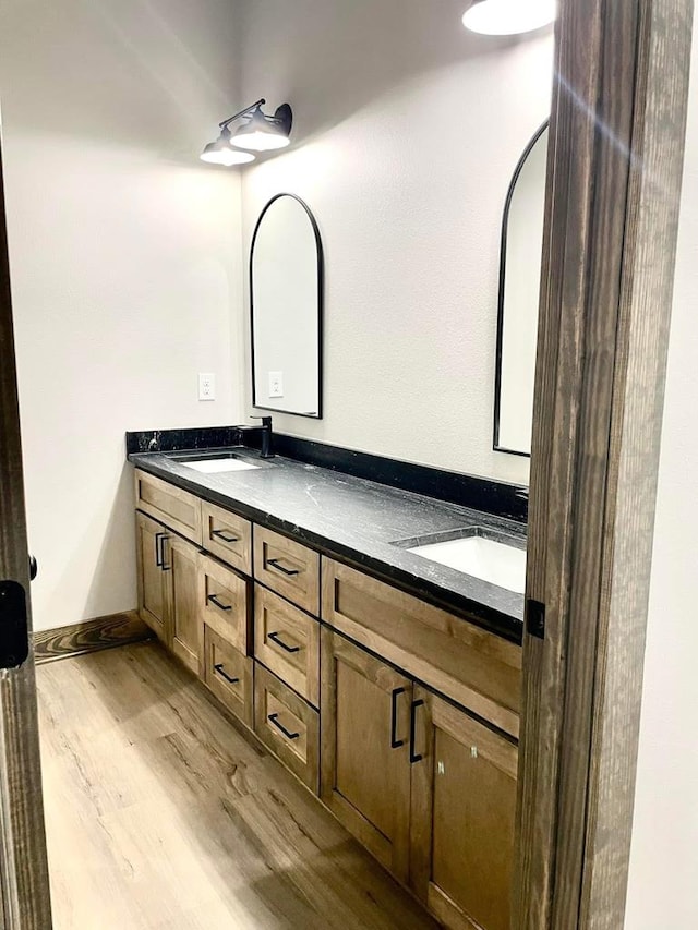 full bath with double vanity, wood finished floors, and a sink