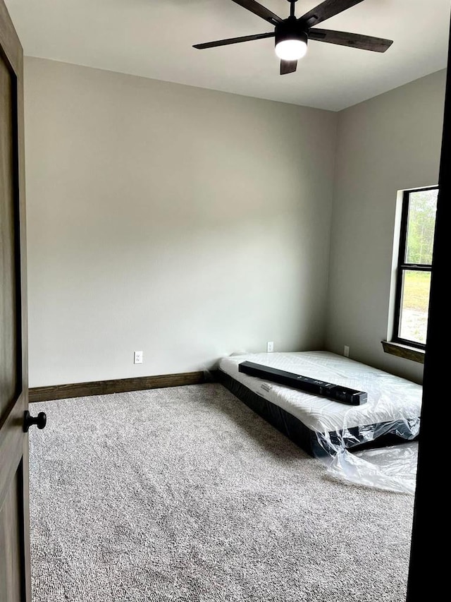 unfurnished bedroom with baseboards, carpet flooring, and ceiling fan