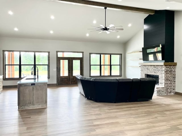 living room with vaulted ceiling with beams, ceiling fan, light wood finished floors, a fireplace, and recessed lighting